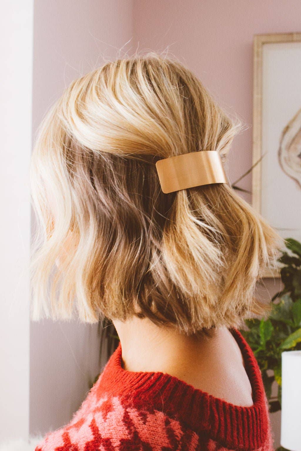 Person with blonde hair wearing a gold barrette, back view, indoor setting