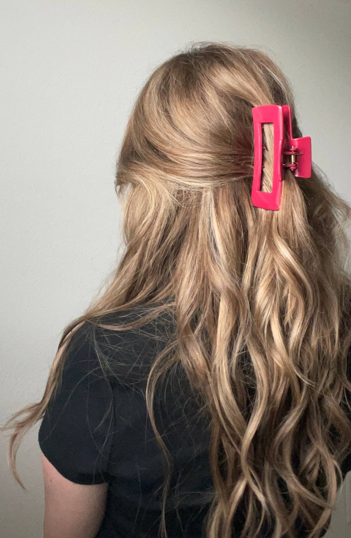 Woman with long wavy blonde hair wearing a silicone rectangle claw clip in a half-up style