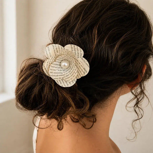 Detail of handmade book page flower hair clip showing printed text petals and lightweight clip base