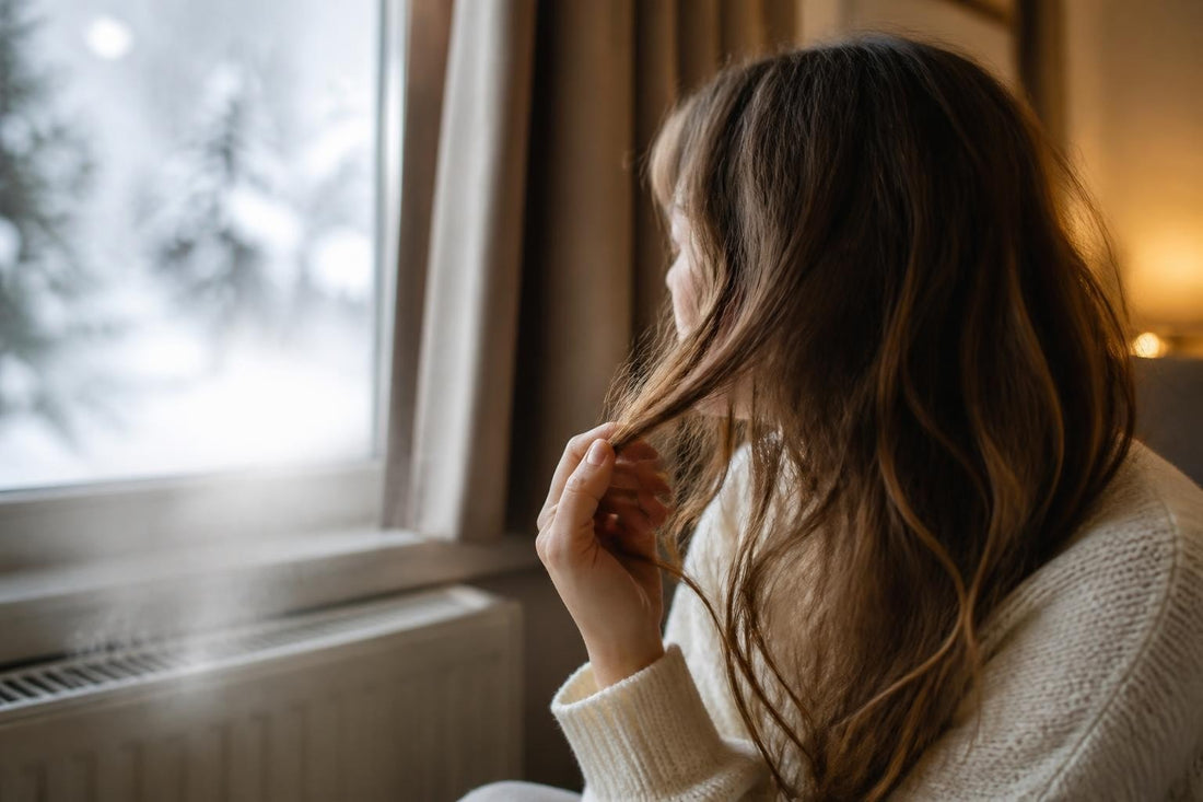 Woman battling dry, brittle winter hair from cold air and indoor heating, restoring moisture with cosmetologist-approved care, The Pixie Garden