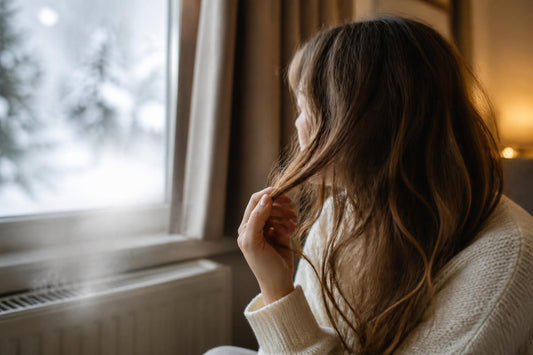 Woman battling dry, brittle winter hair from cold air and indoor heating, restoring moisture with cosmetologist-approved care, The Pixie Garden