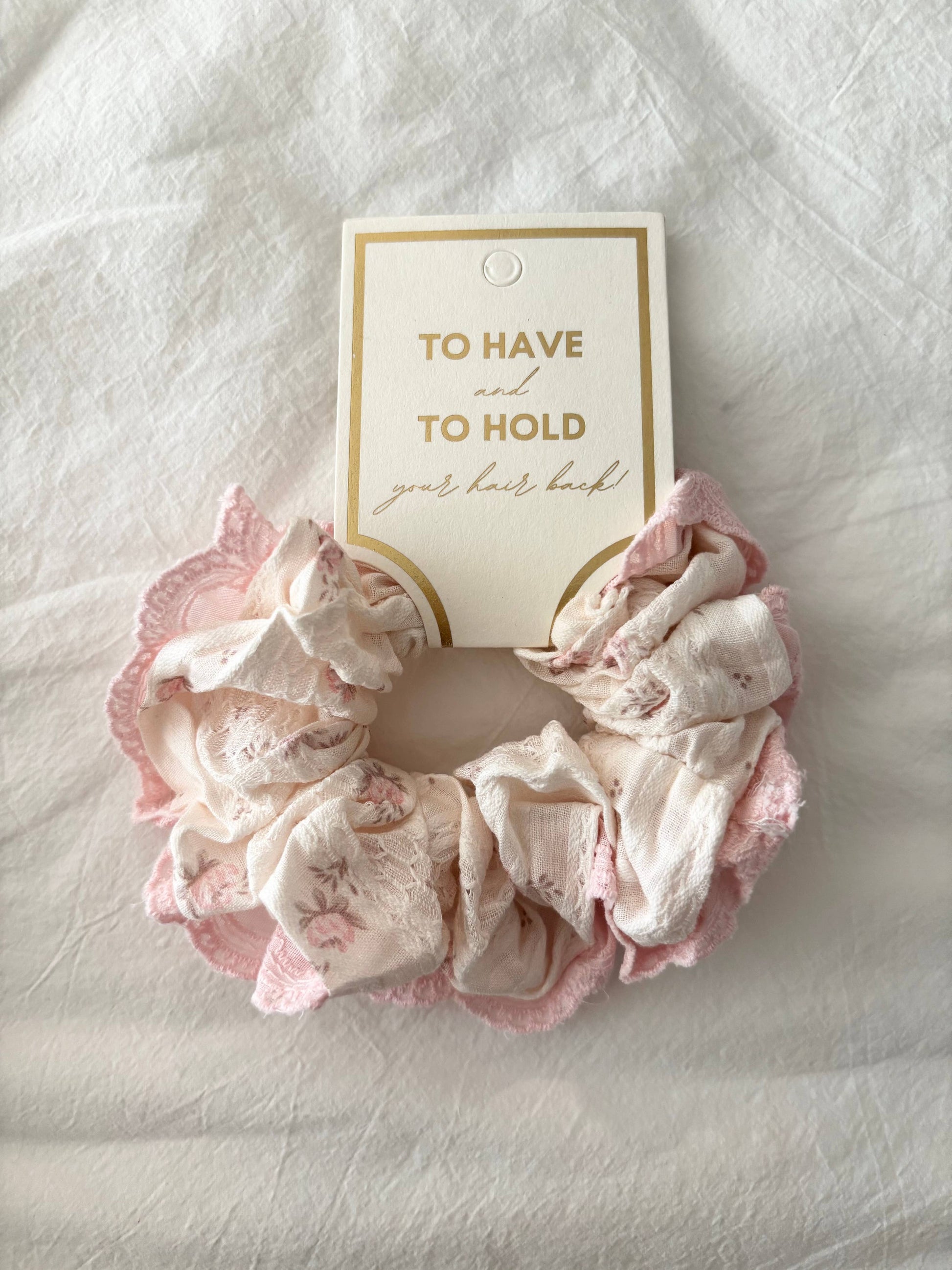 Pink lace scrunchie on a white background with a card that says 'To Have and To Hold Your Hair Back'.