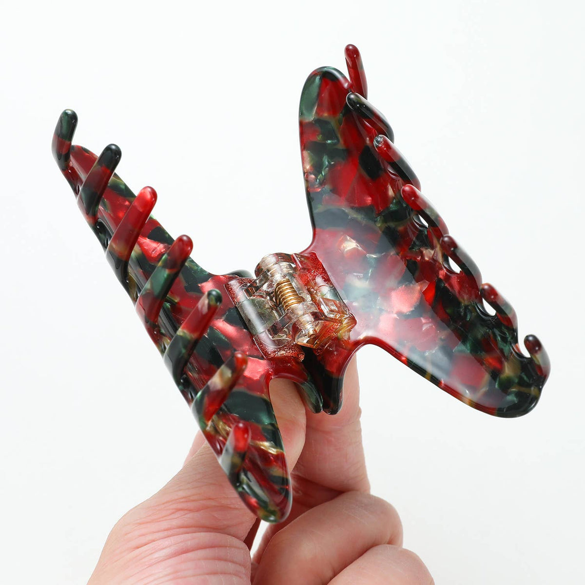 Hand holding a Vintage Christmas claw clip to show its small to medium scale