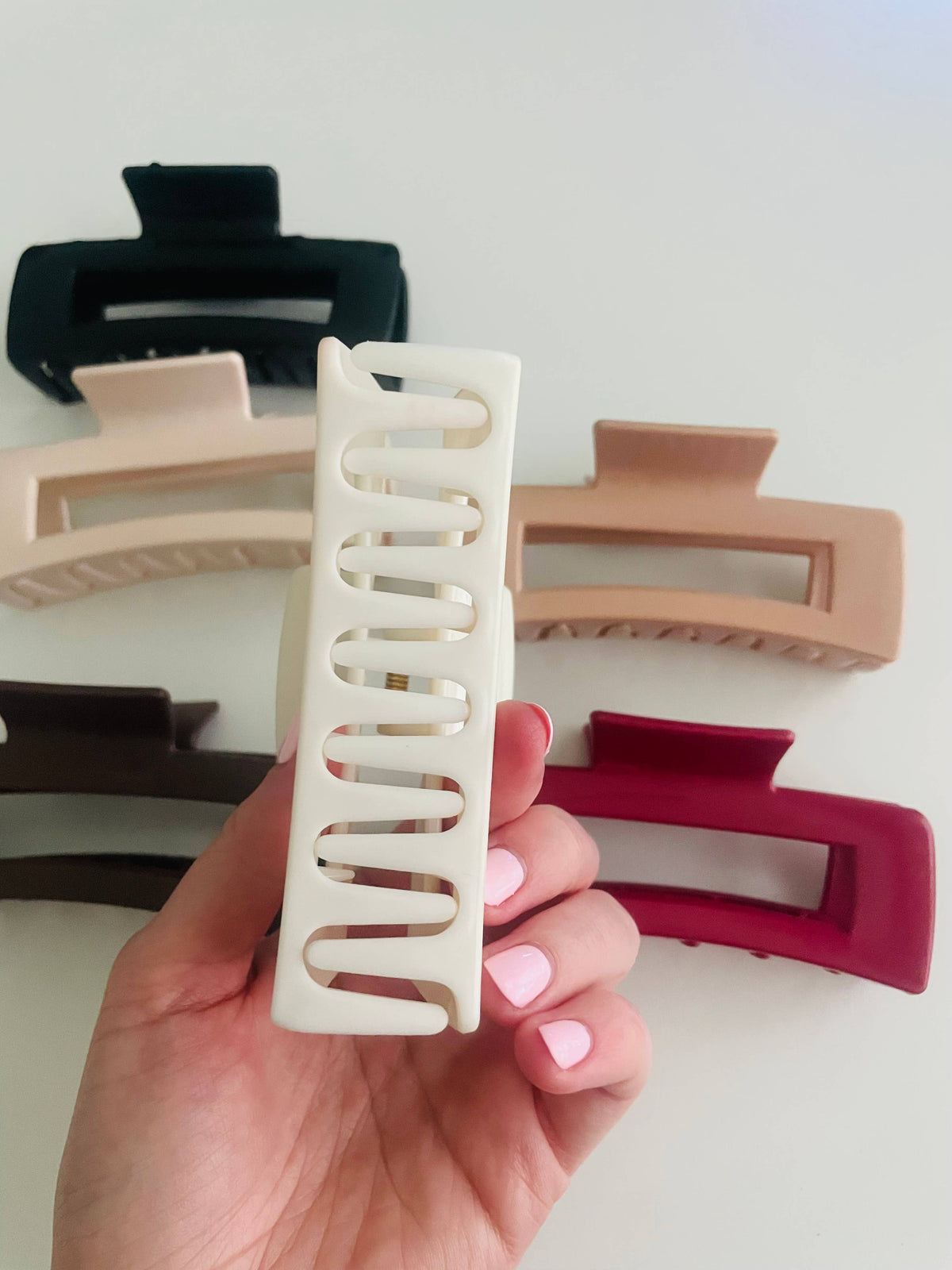 Hand holding a silicone rectangle claw clip, showing the teeth and soft matte finish