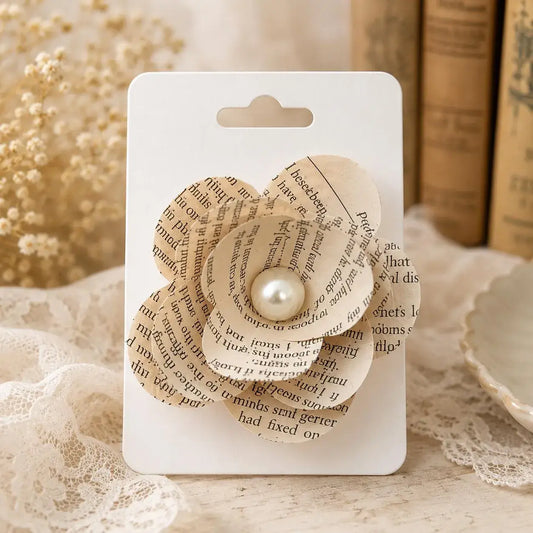 Handmade book page flower hair clip with layered paper petals and faux pearl center, crafted from reclaimed book pages | The Pixie Garden