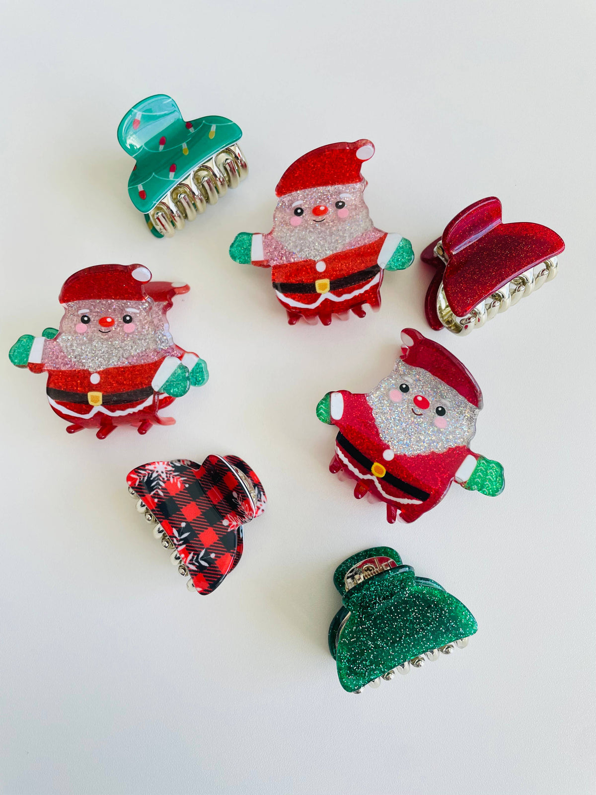 Mini Christmas claw clips shown together, covering the Santa, Flannel, Christmas Tree Lights, Red Sparkle and Green Sparkle designs