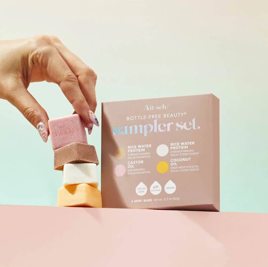 Hand holding a pink bar of soap next to a 'kitsch' box on a light background