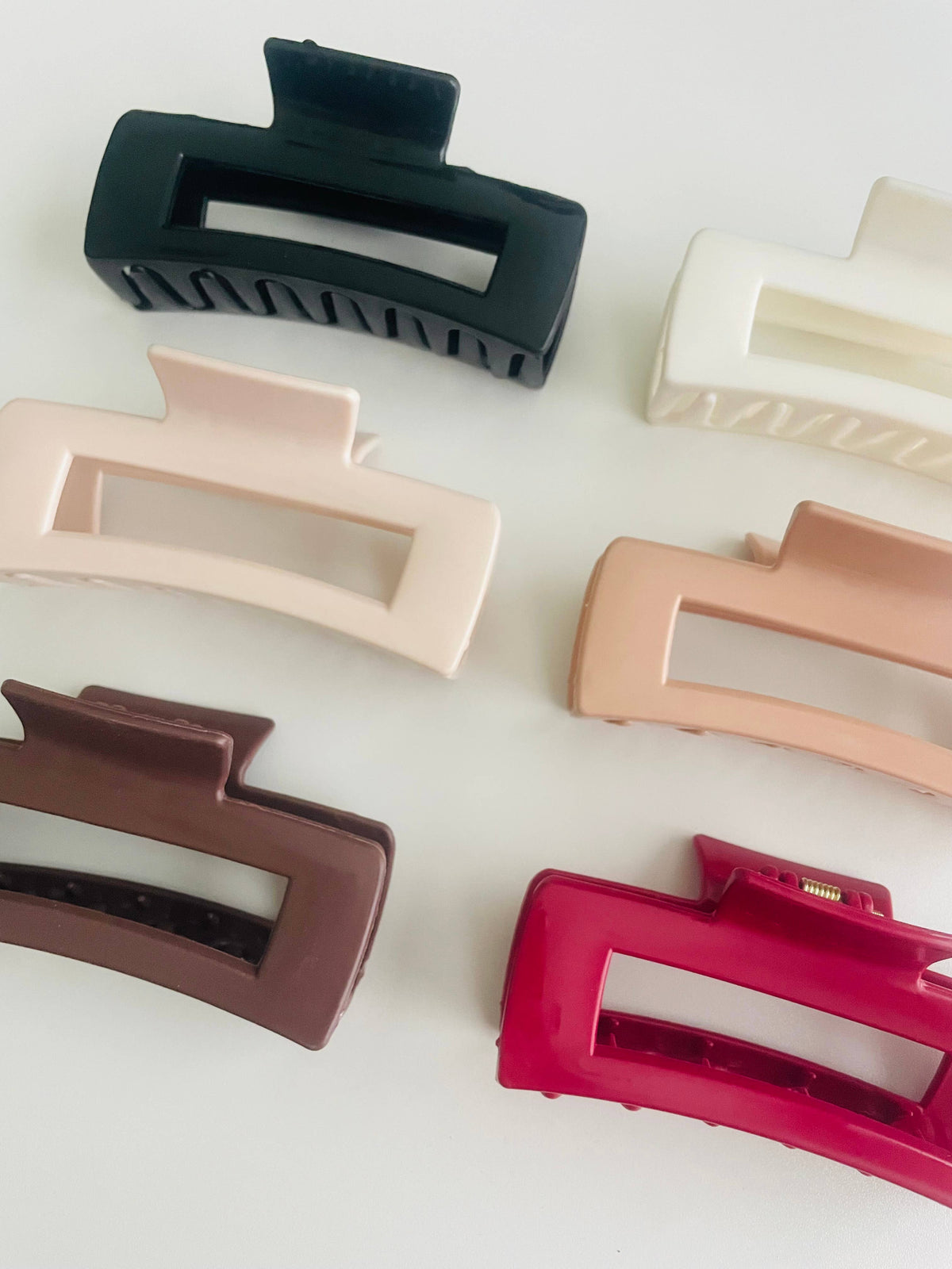 Silicone bendable rectangle claw clips in brown, white and red on a white background