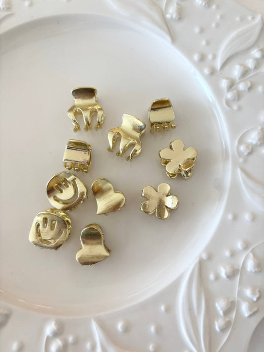 white plate with gold metal mini claw clips in smiley faces, hearts, and flowers.