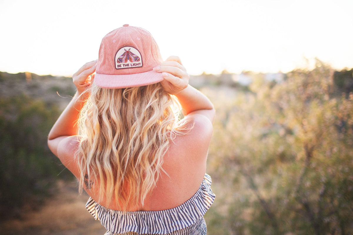 Back view of a woman in a striped top wearing the Be The Light corduroy snapback outdoors